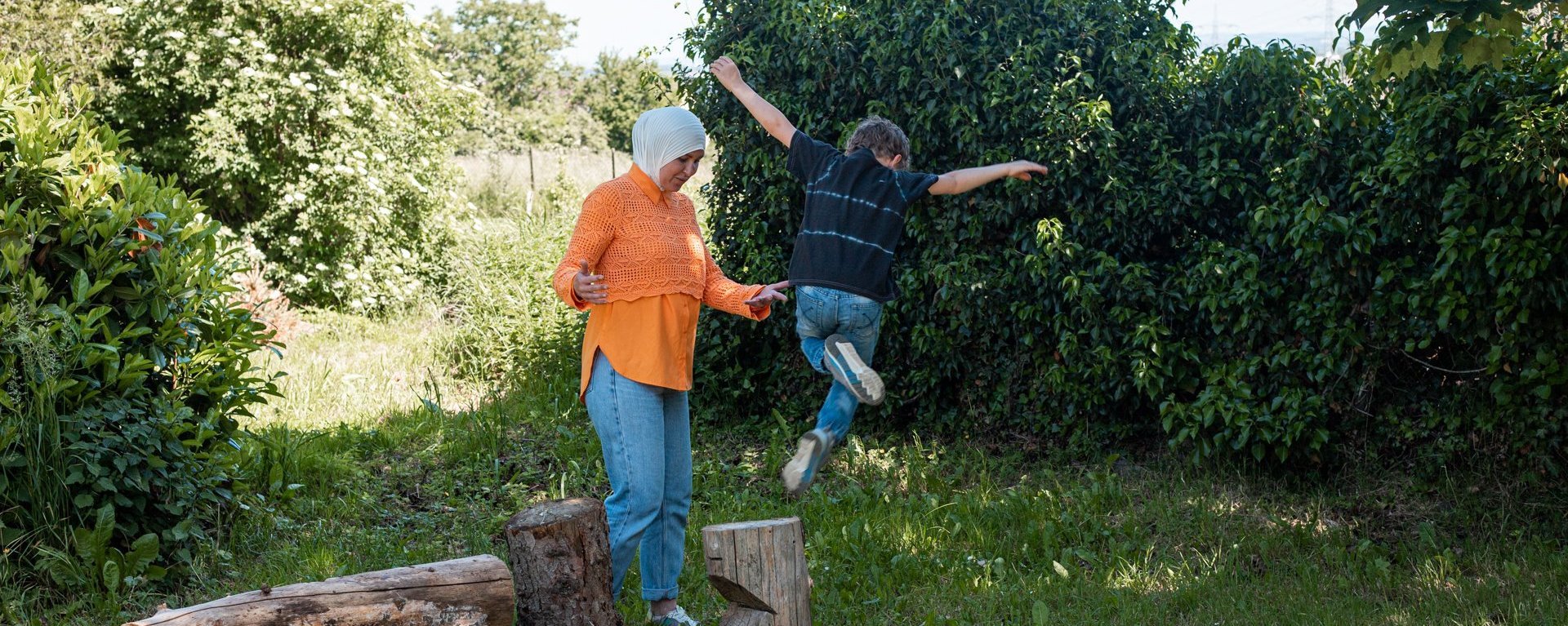 Erzieherin und Junge spielen im Grünen.