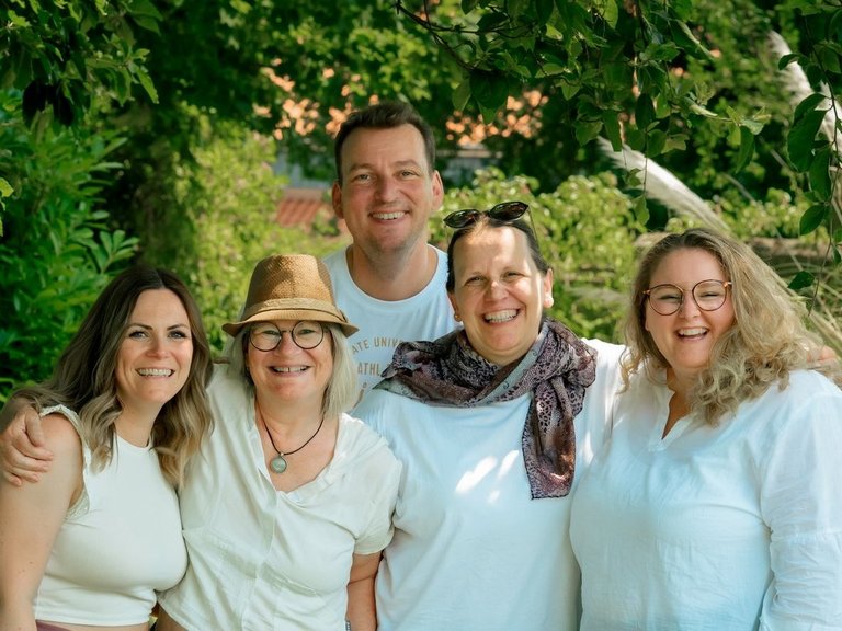 Ein Gruppenfoto von vier lachenden Frauen und einem Mann im Garten.